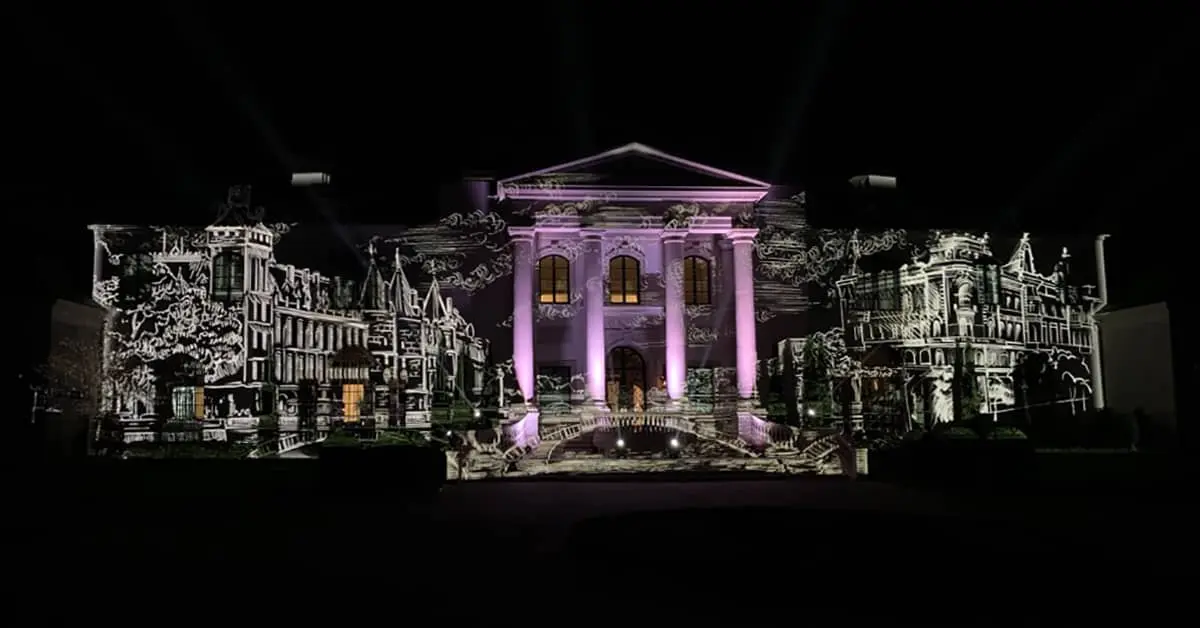 The white house is lit up with purple lights at night.