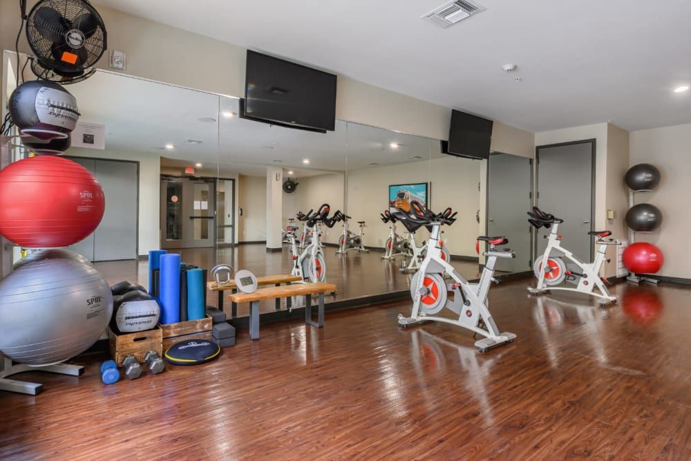 A fitness center with a lot of exercise equipment and a large mirror at The 704 in Austin TX.