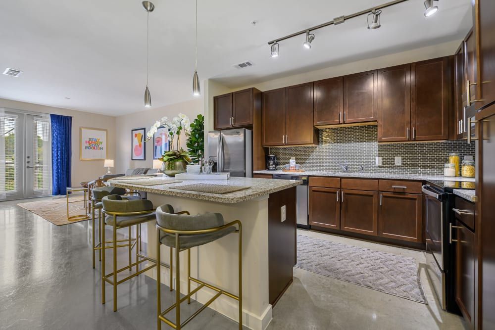 Spacious kitchen with stainless steel appliances, wooden cabinets, granite counter tops, and a large island at The 704 in South Lamar Austin, TX.