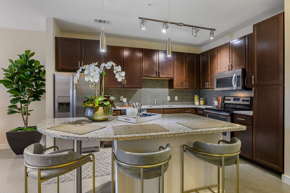 Apartment community kitchen with a large island, stools, a refrigerator, and a microwave at The 704 in South Lamar Austin, TX.