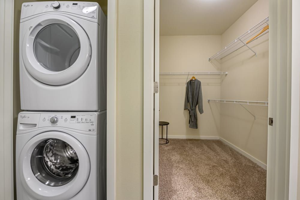 A washer and dryer are stacked on top of each other right next to a walk-in closet at The 704 in Austin TX.