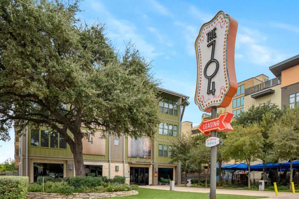 A large neon sign is sitting in front of the apartment building at The 704 in South Lamar Austin, TX.