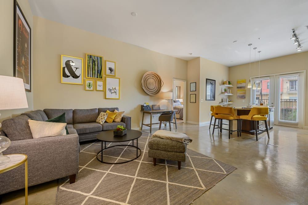 Apartment living room with a couch, chairs, a table, and a rug at The 704 in South Lamar Austin, TX.