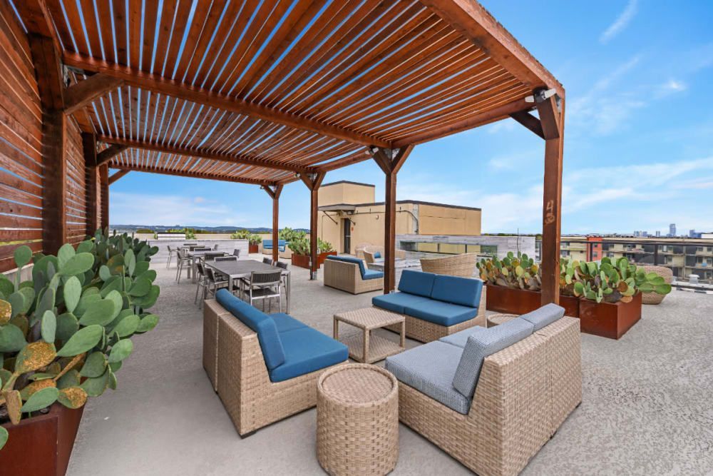 Outdoor patio with a wooden pergola and wicker furniture at The 704 in Austin TX.