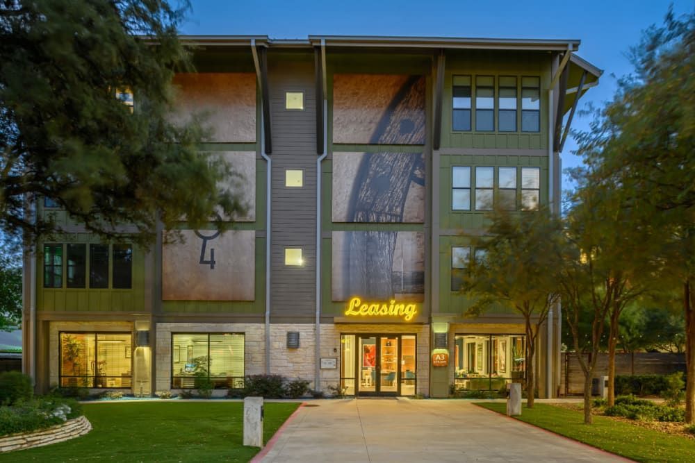 Exterior of the apartment building with a lot of windows and trees in front of it at The 704 in South Lamar Austin, TX.