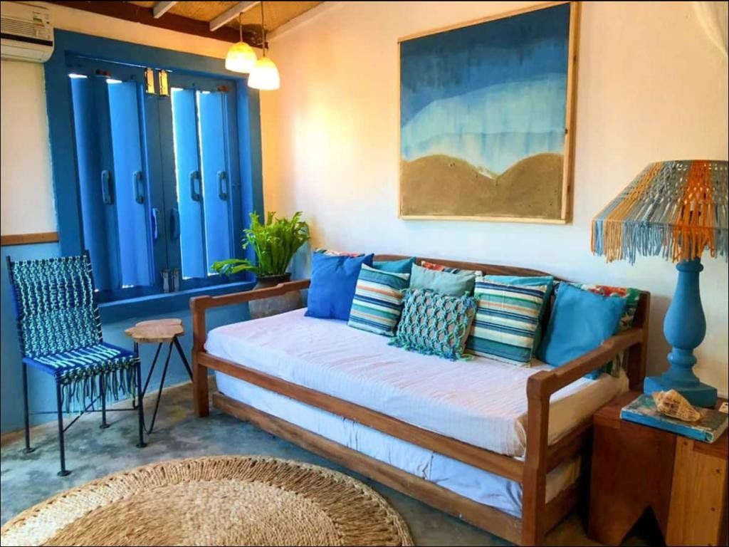 uma sala com sofá, cadeira, luminária e quadro na parede.