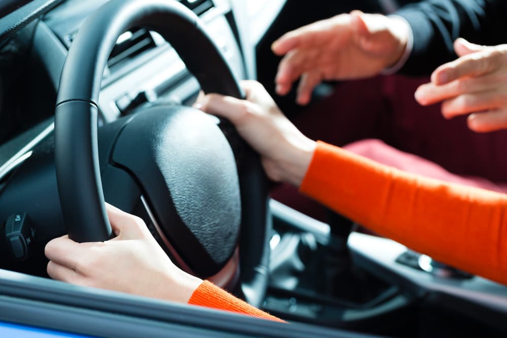 A Woman is Driving a Car and Talking to Another Person — Howards Professional Driving School In Gordonvale, QLD