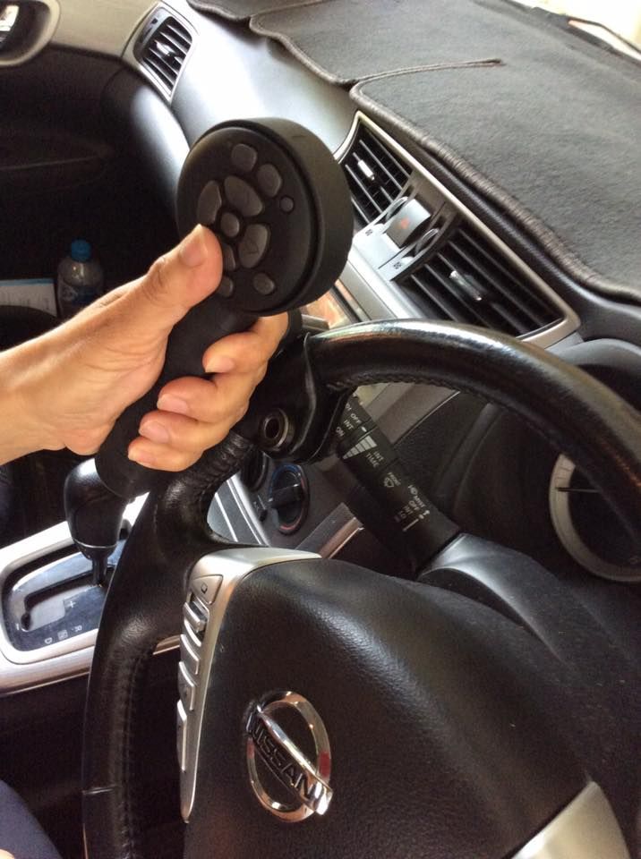 A Person is Holding a Steering Wheel in a Nissan Car — Howards Professional Driving School In Gordonvale, QLD