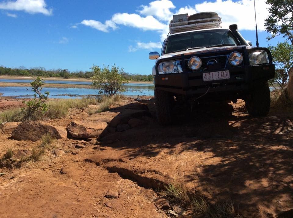 A Car is Parked on a Dirt Road Near a Body of Water — Howards Professional Driving School In Innisfail, QLD