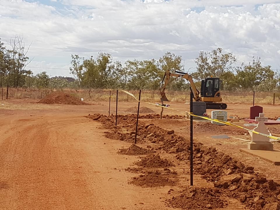 Construction site with a small excavator digging trenches.