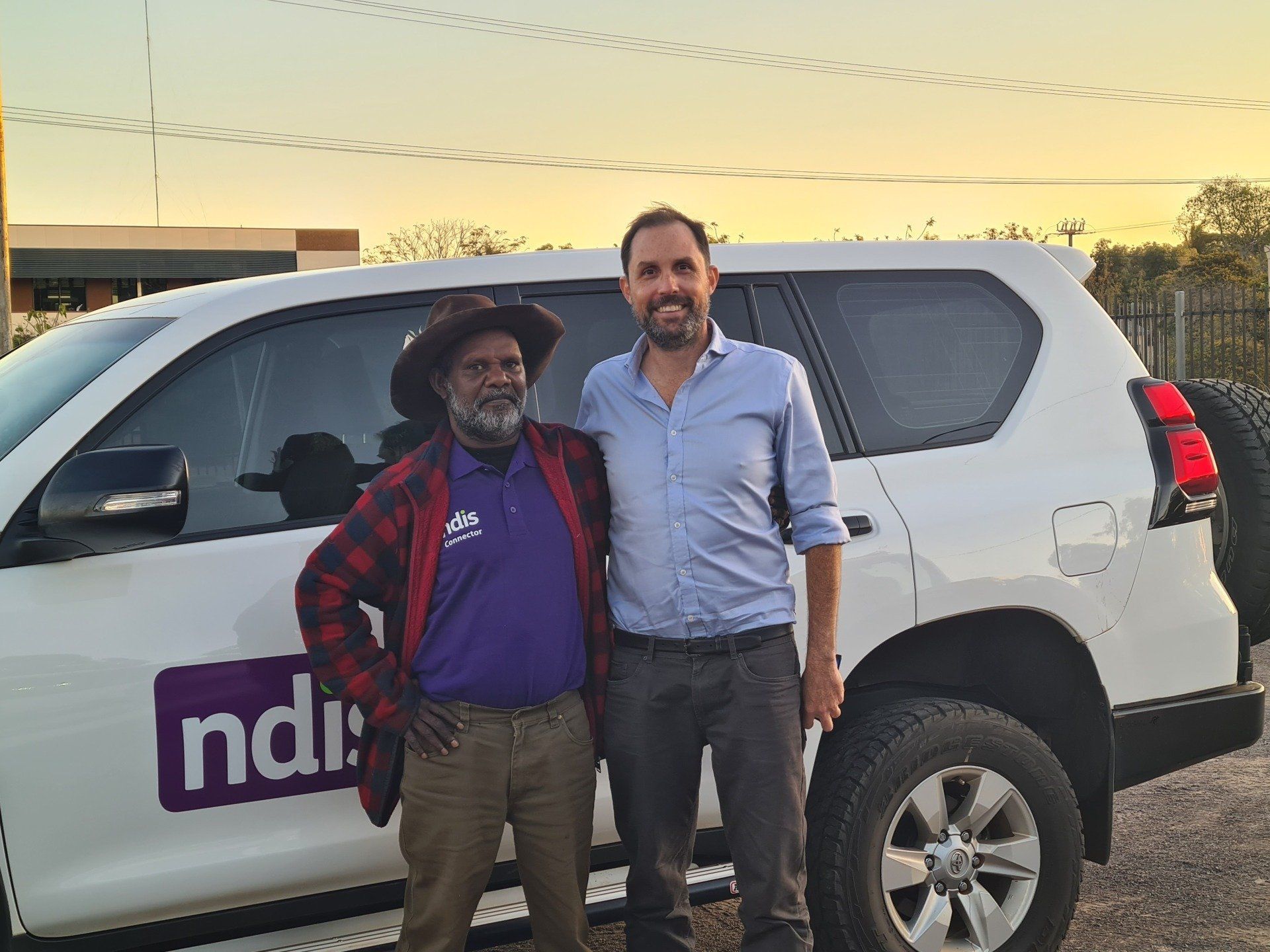 Two men stand beside a white SUV with
