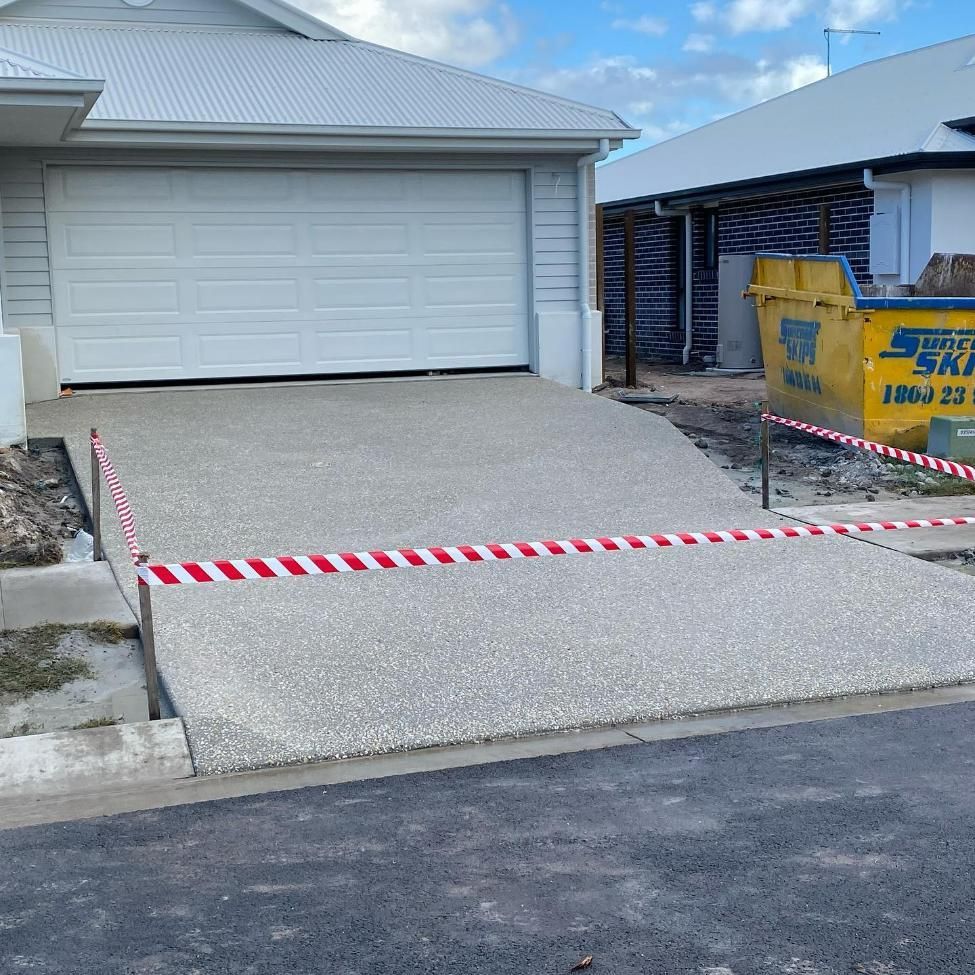 House With a White Garage Door and a Yellow Dumpster in Front of It — Construction 33 in Maroochydore, QLD