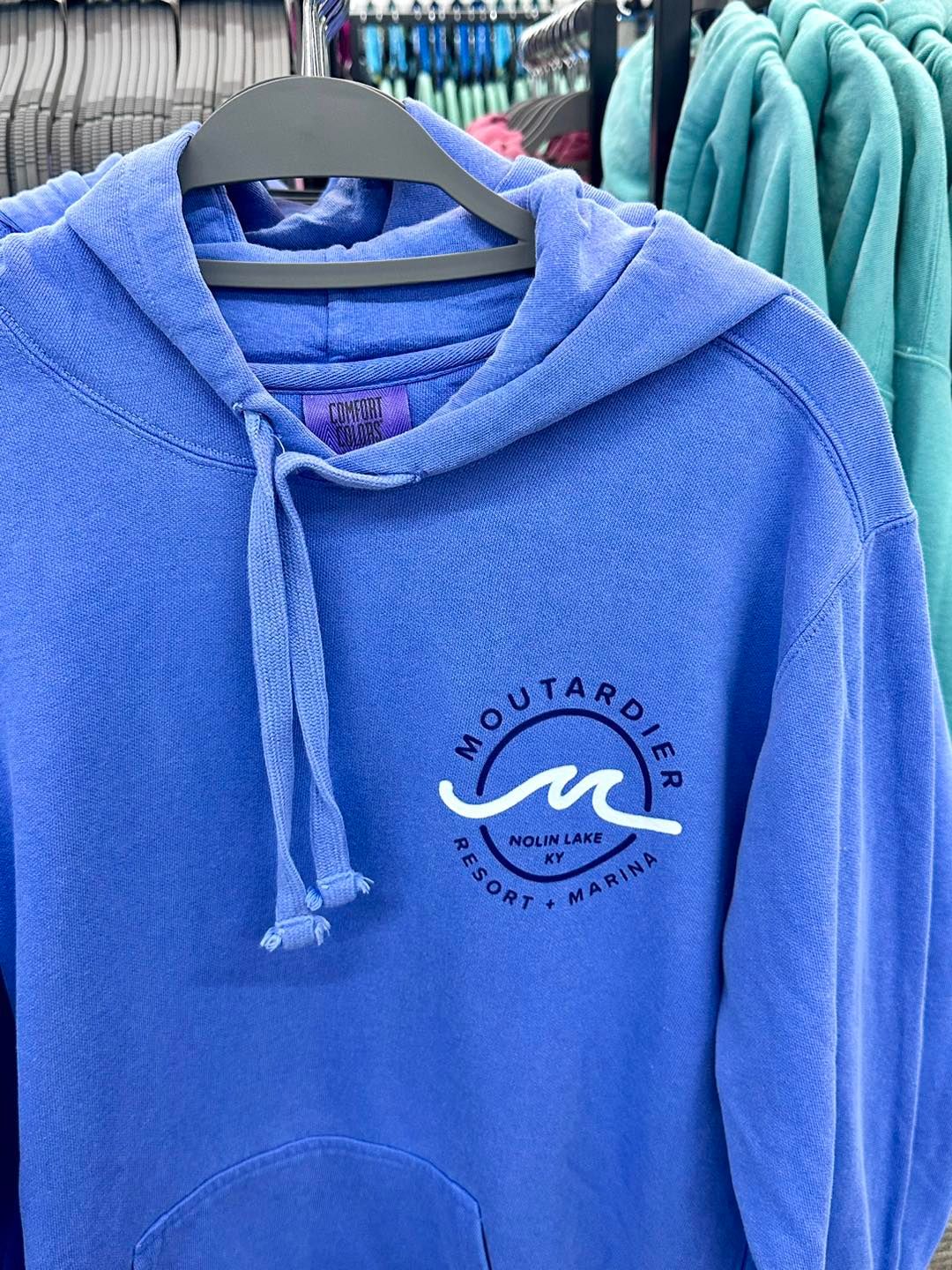 A purple hoodie is hanging on a hanger in a store.