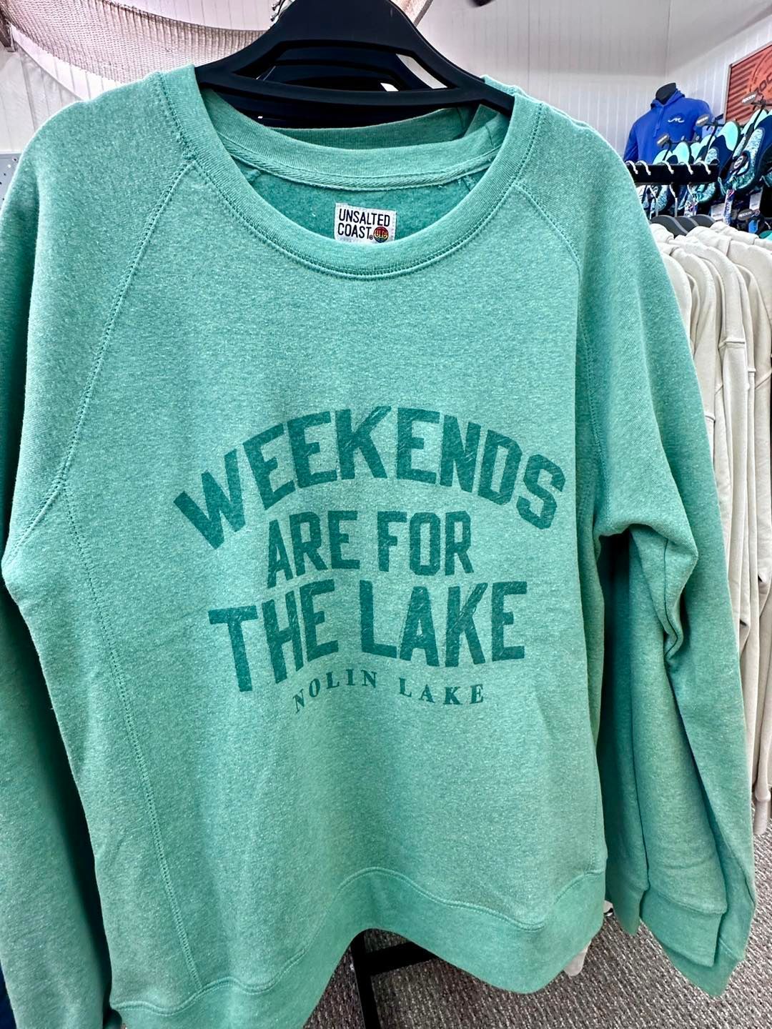 A green sweatshirt that says `` weekends are for the lake '' is hanging on a hanger.