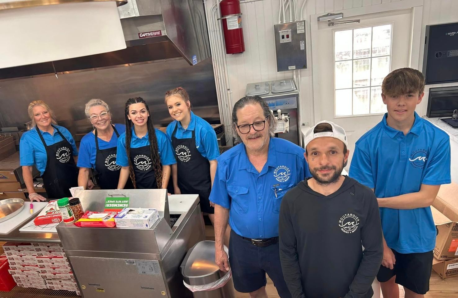 A group of people are posing for a picture in a kitchen.