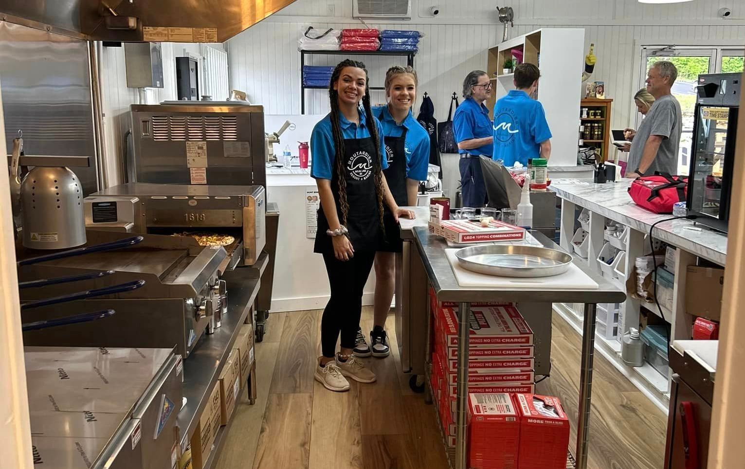 A group of people are standing in a kitchen.