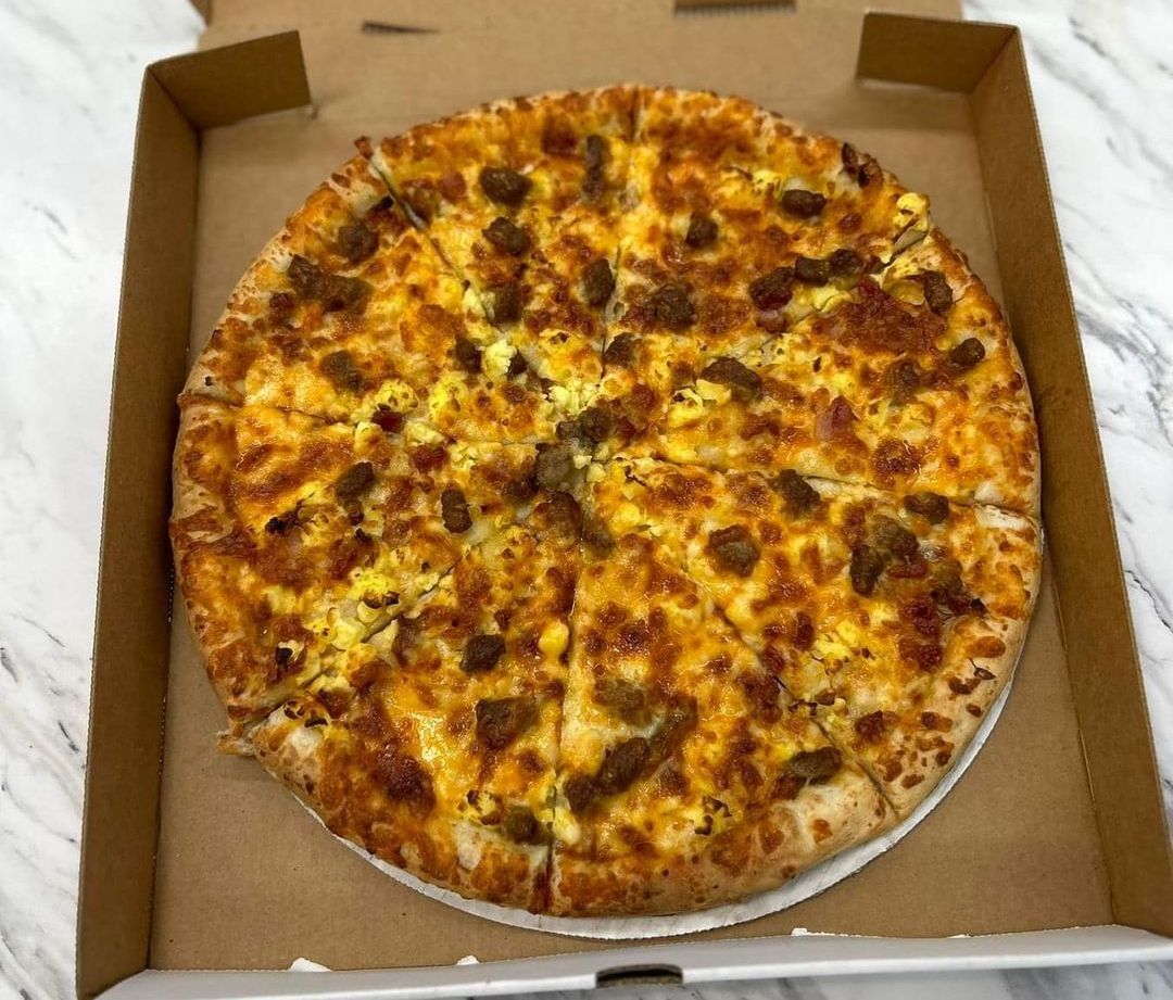 A pizza with sausage and cheese is in a cardboard box.