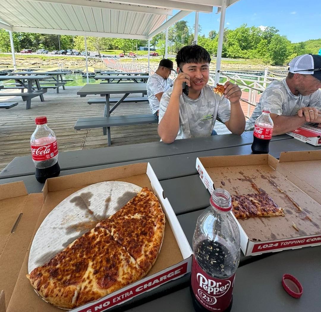 A man is sitting at a table eating pizza and drinking coca cola.