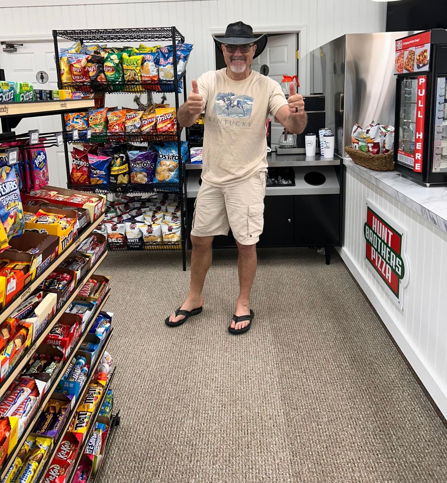 A man in a cowboy hat is giving a thumbs up in a store