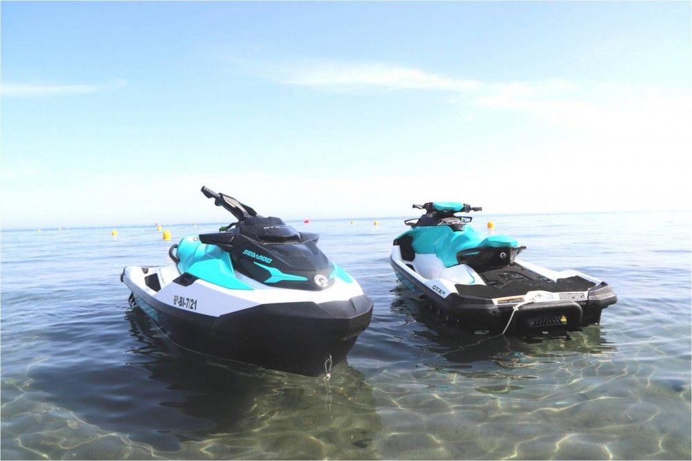 Two jet skis are floating on top of a body of water.