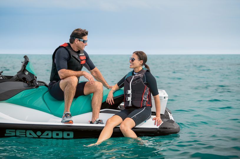 A man and a woman are sitting on a jet ski in the ocean.