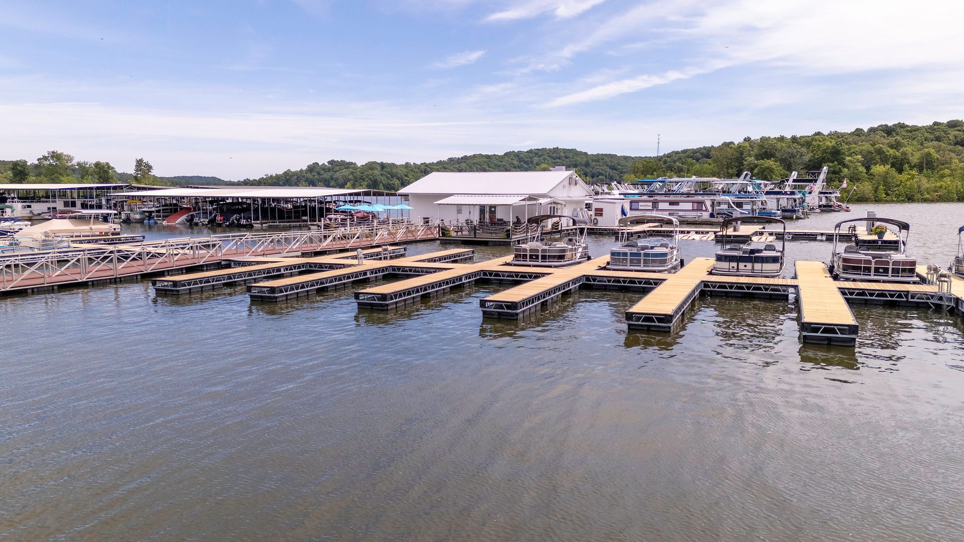 There are many boats docked at a marina on a lake.