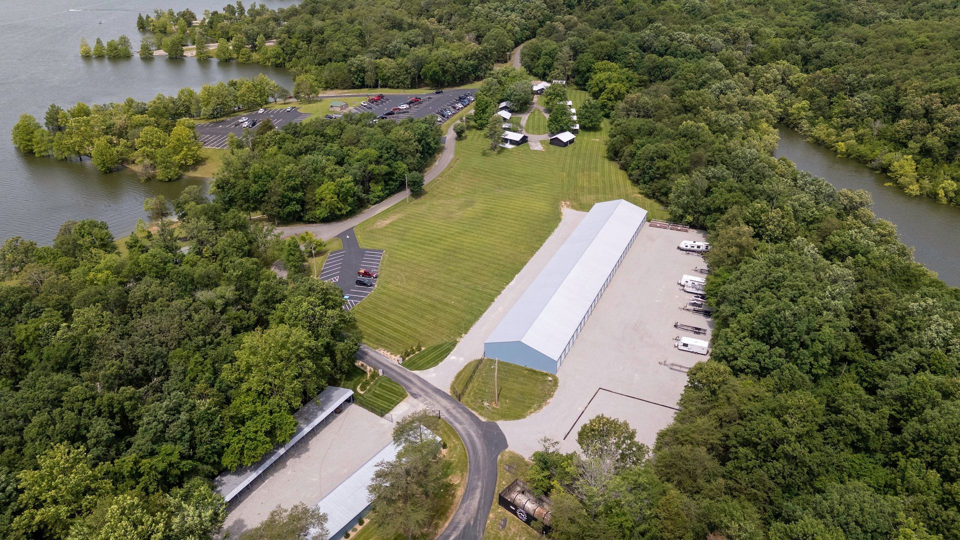 An aerial view of a large building surrounded by trees and a lake.
