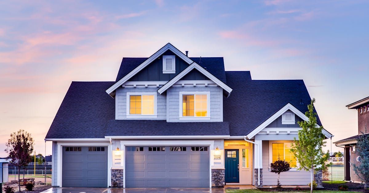 A large house with a blue roof and a blue door is lit up at sunset.