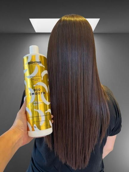 Persona sosteniendo una botella de producto para alisar el cabello, mostrando un cabello castaño, liso y elegante.