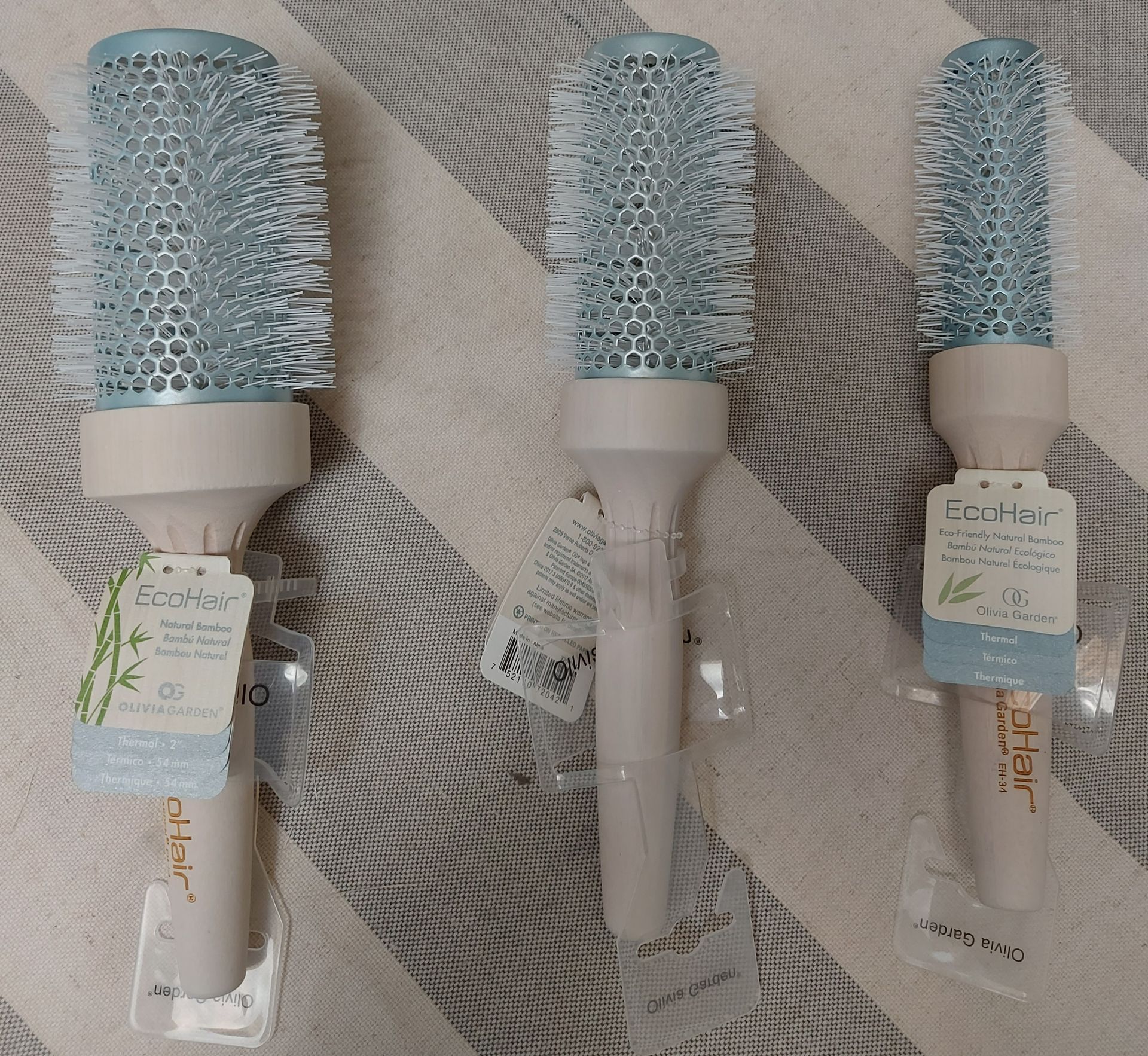 Tres cepillos de pelo redondos de color azul claro y beige.