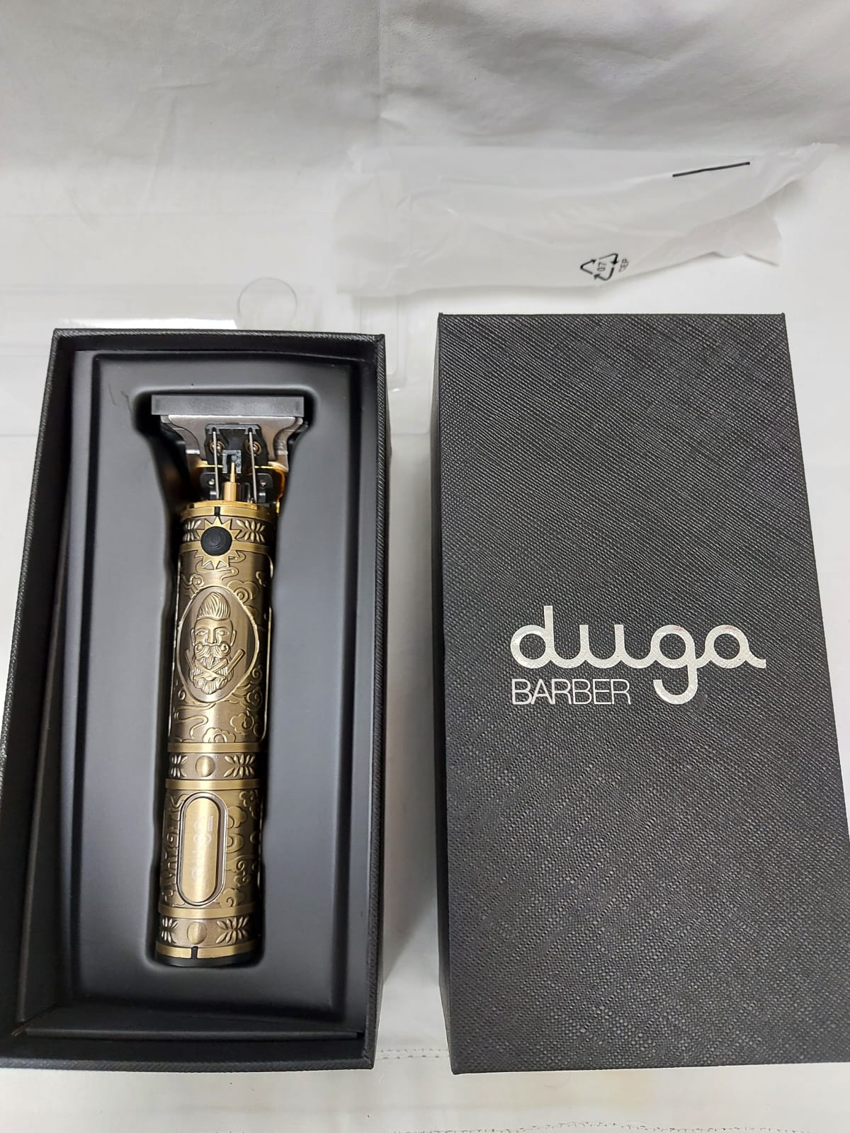 Cortadora de pelo de color dorado en caja negra, con el nombre