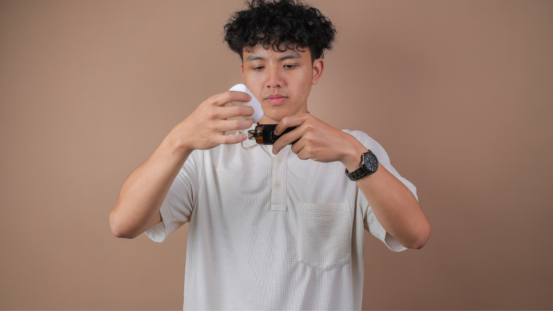 A person holding a vape mod and refilling it with e-liquid, preparing to vape.
