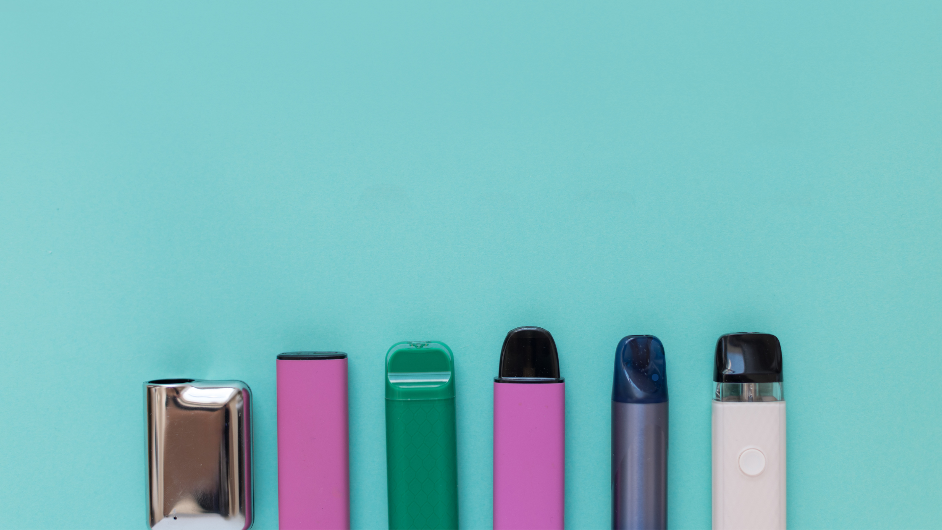 A variety of colorful disposable vape devices arranged neatly on a teal background, showcasing different models available for beginners.