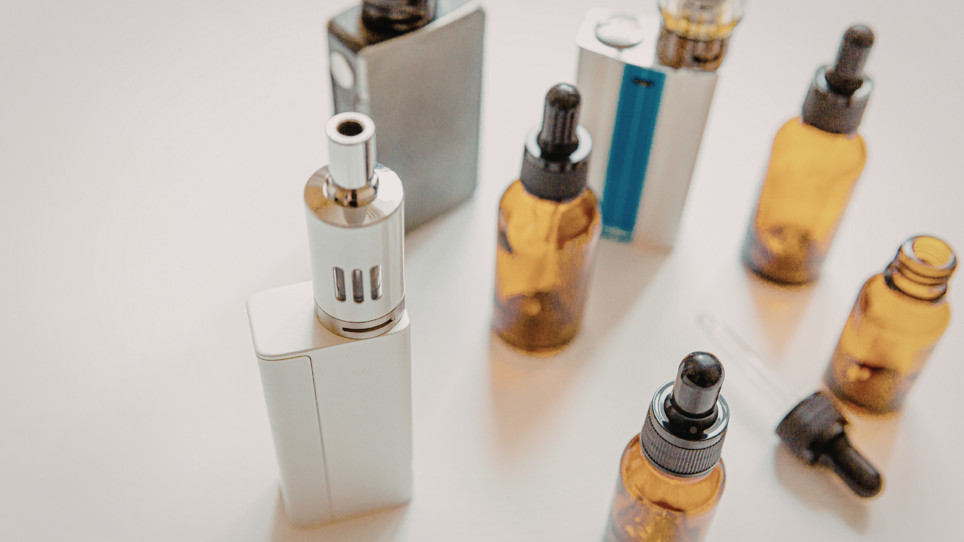 A collection of vaping devices and e-liquid bottles, including mods, coils, and amber dropper bottles, showcasing a variety of products for vapers.