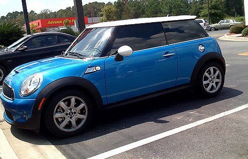 A blue mini cooper is parked in a parking lot.