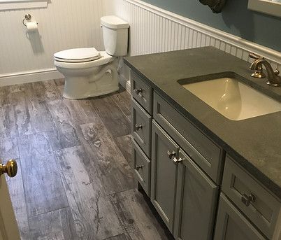 A bathroom with a toilet , sink and cabinets.