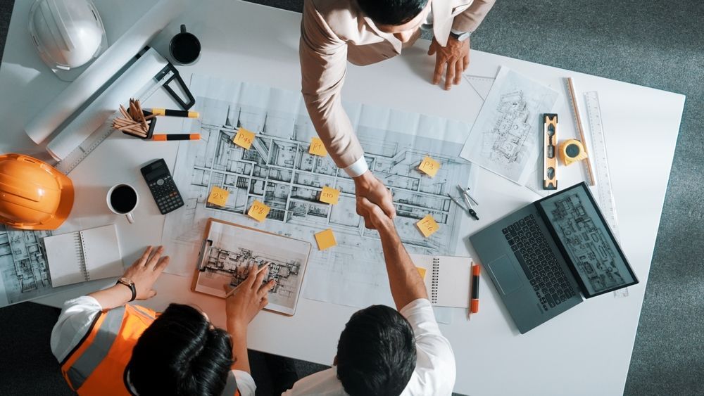 A group of engineers are shaking hands over a table.