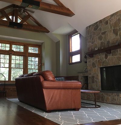 A living room with a brown leather couch and a stone fireplace.