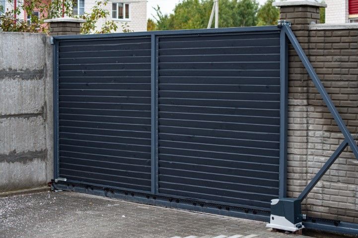 Dark gray horizontal sliding gate in front of a concrete and brick wall.