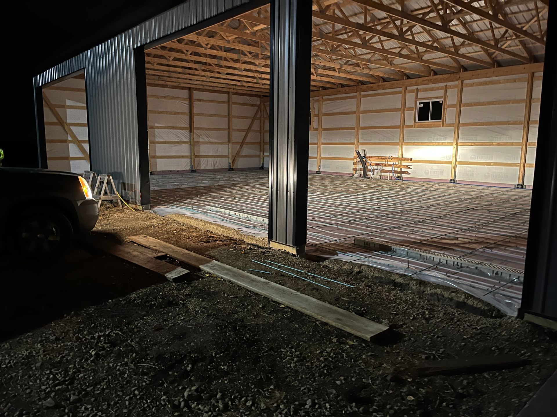 A truck is parked in front of a building that is being built at night.