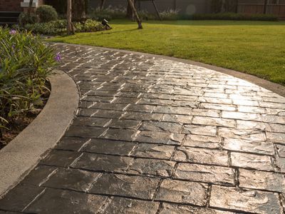 A stamped concrete walkway leading to a lush green lawn.