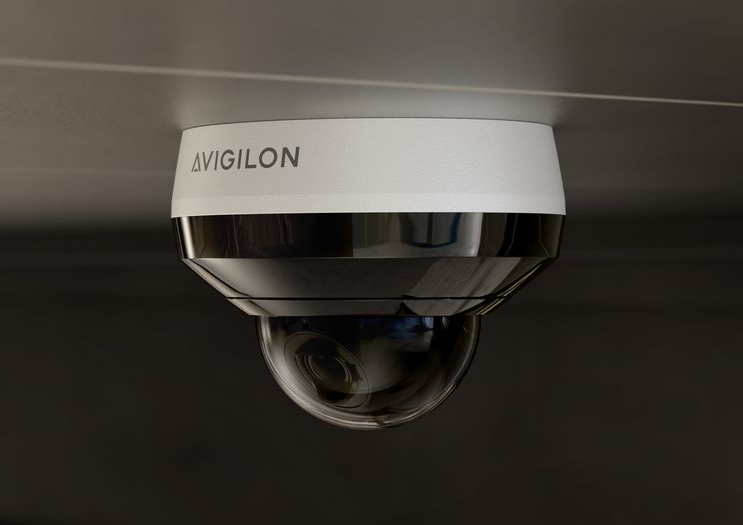 Close-up of a ceiling-mounted security camera with a white base and a black, dome-shaped lens.
