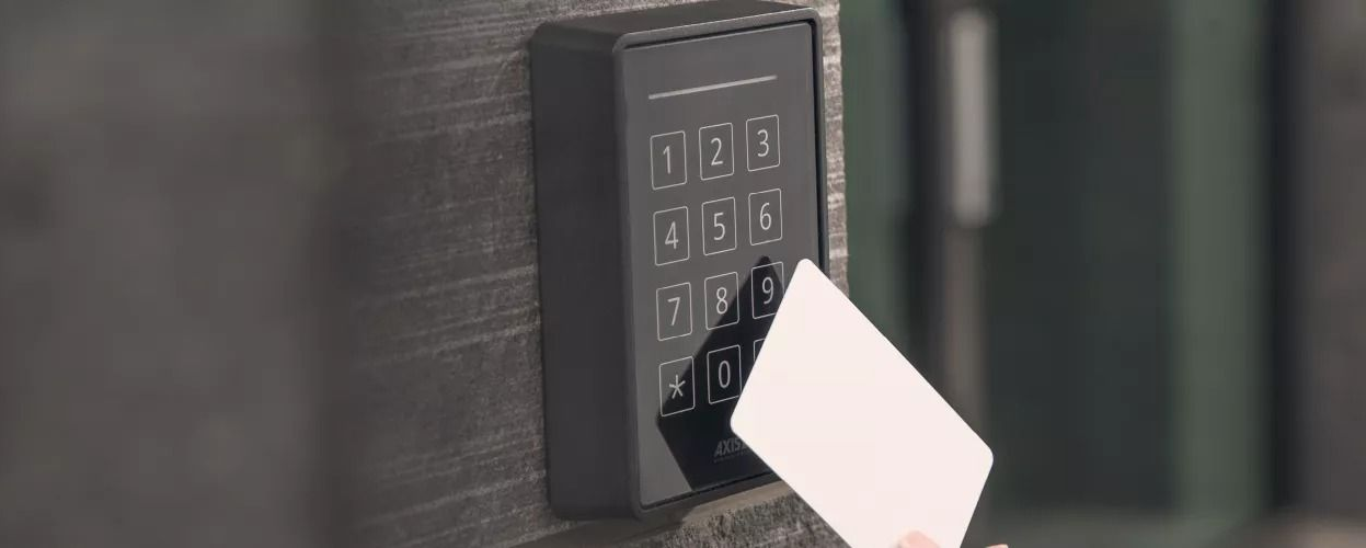 A hand is using a white card to scan a keypad on a dark surface.