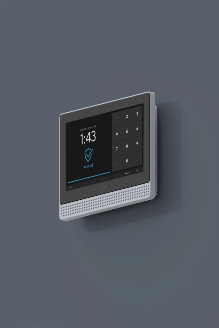 Security system control panel mounted on a gray wall; shows time, keypad, and armed status.