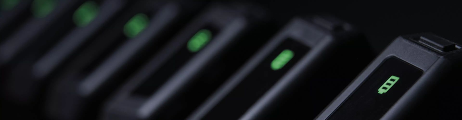 Close-up of several charging devices with green battery indicator lights.