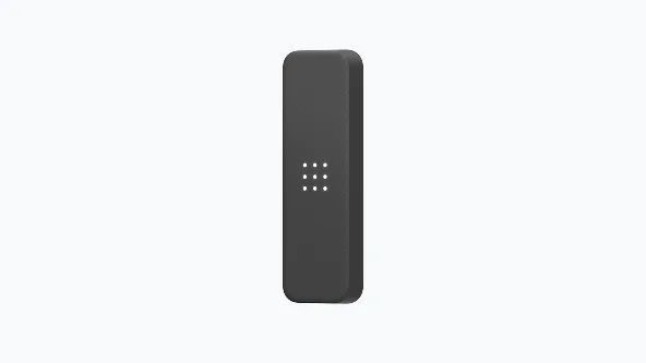 Dark gray, rectangular remote with rounded corners and nine small white dots in the center.