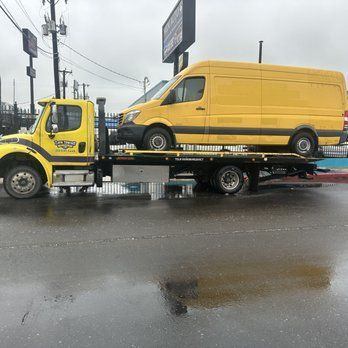 A yellow van is being towed by a tow truck.