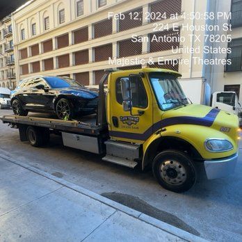 A tow truck with a car on the back is parked on the side of the road.