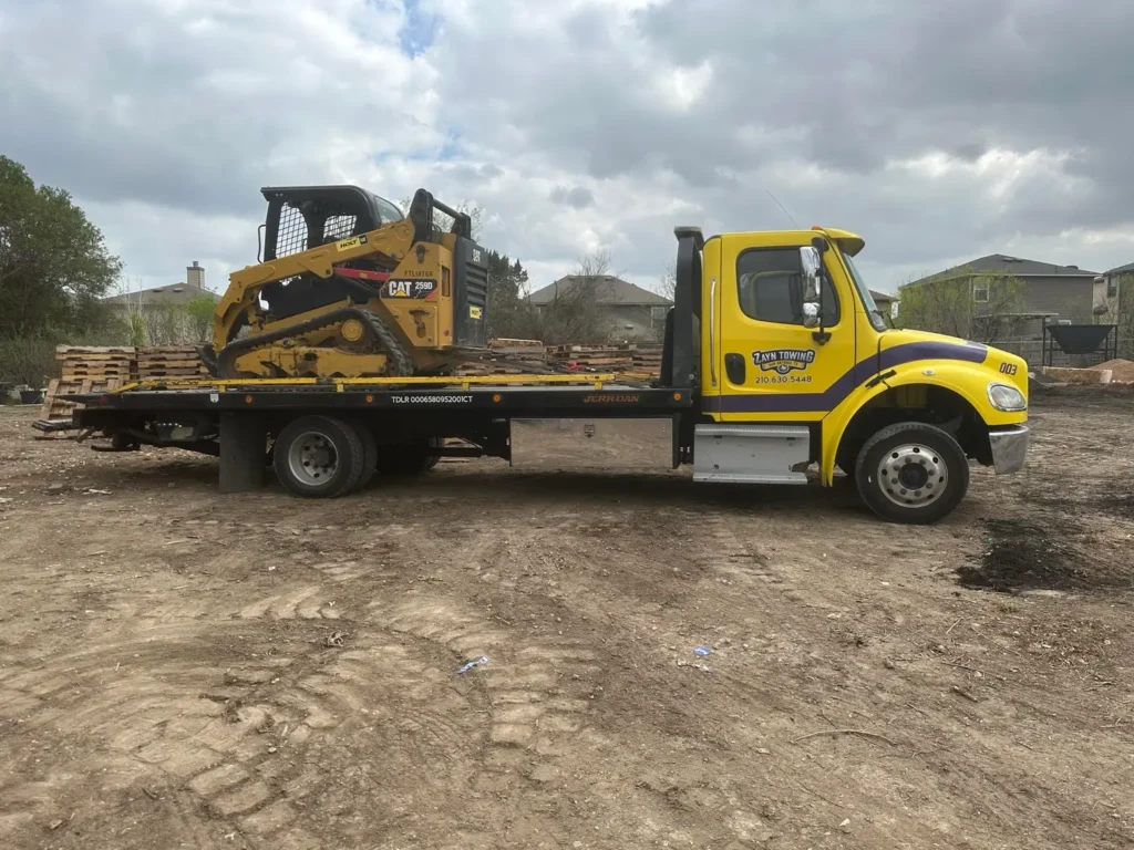 A yellow tow truck is carrying a bulldozer on the back of it.