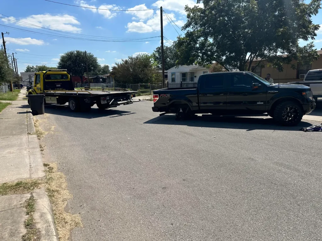 A black truck is being towed by a yellow tow truck